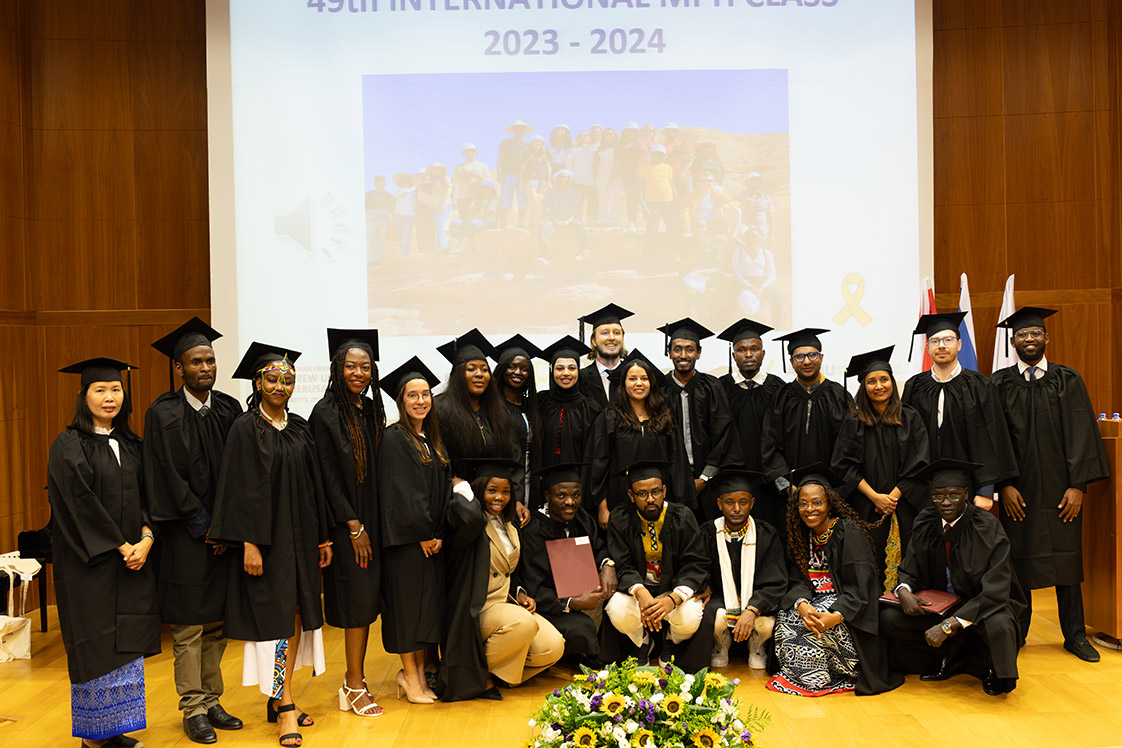 Graduates pose together on the auditorium stage after their graduation ceremony