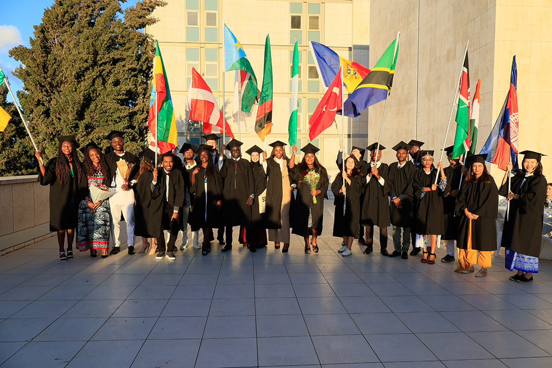 Graduates pose together on the rooftop at Hadassah holding the flags representing their home countries